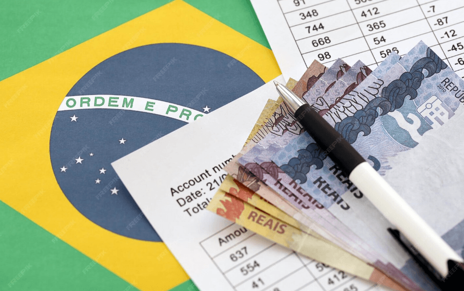 Bandeira do Brasil ao fundo ao lado de cálculos que representam a Receita Federal, cédulas de BRL representam o imposto devido após operações lucrativas com criptomoedas.